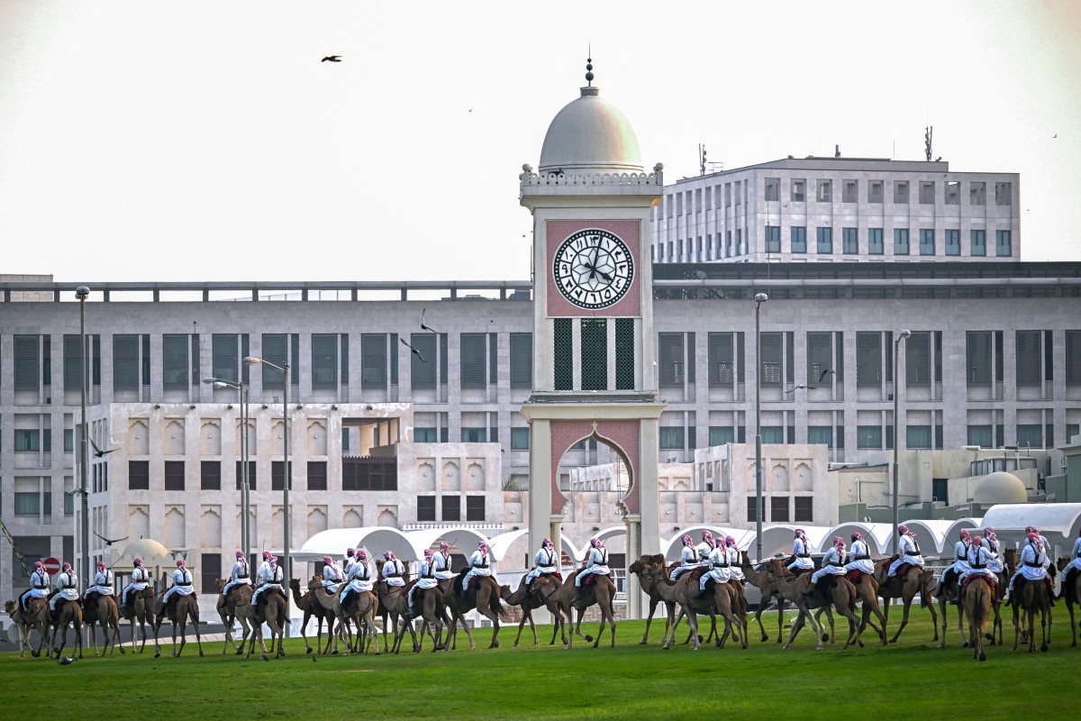 Camel-mounted royal guards patrol around the Amiri Diwan in Doha on November 13, 2025. (Photo by MAHMUD HAMS / AFP)