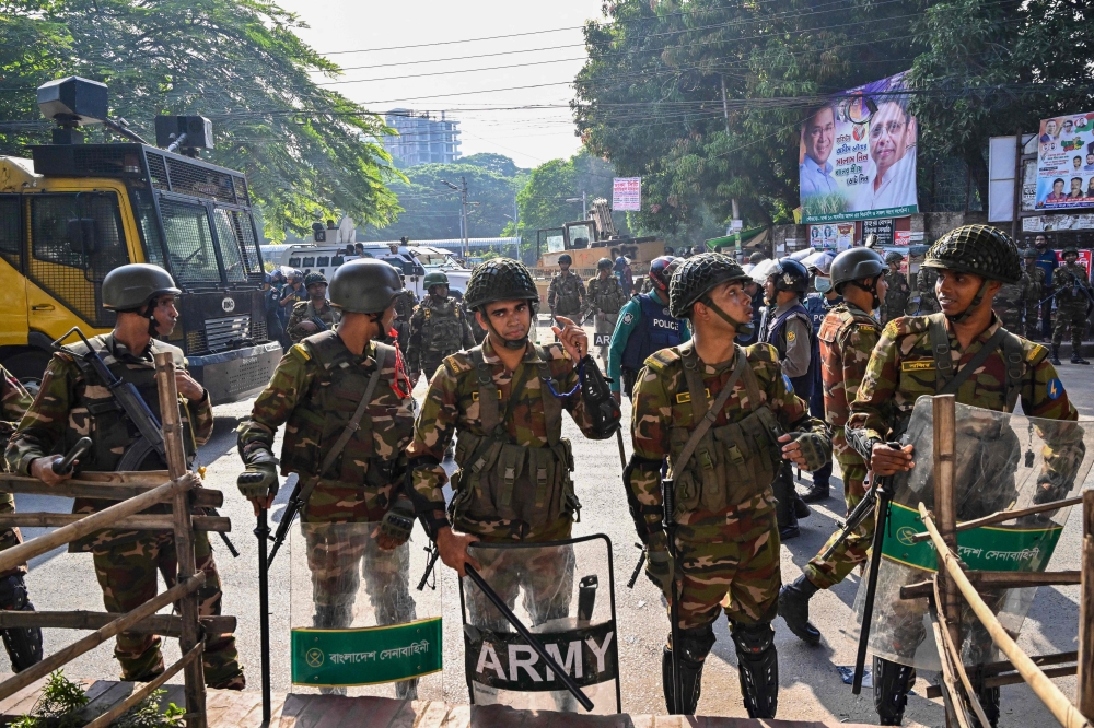Security personnel stand guard as demonstrators attempt to demolish the residence of Sheikh Mujibur Rahman in Dhaka on November 17, 2025. (Photo by Munir Uz Zaman / AFP)