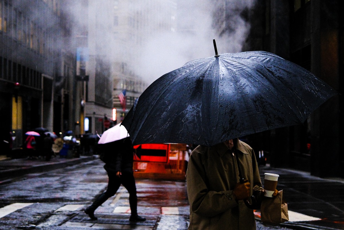 People walk on the street as the rain pours in the Manhattan borough of New York City on November 19, 2025. (Photo by CHARLY TRIBALLEAU / AFP)
