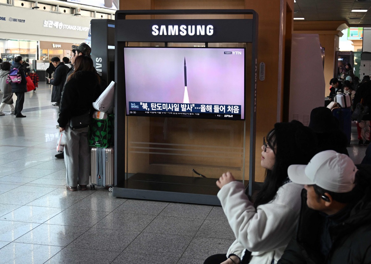 People sit in front of a television screen showing a news broadcast with file footage of a North Korean missile test, at a train station in Seoul on January 4, 2026. Photo by Jung Yeon-je / AFP
