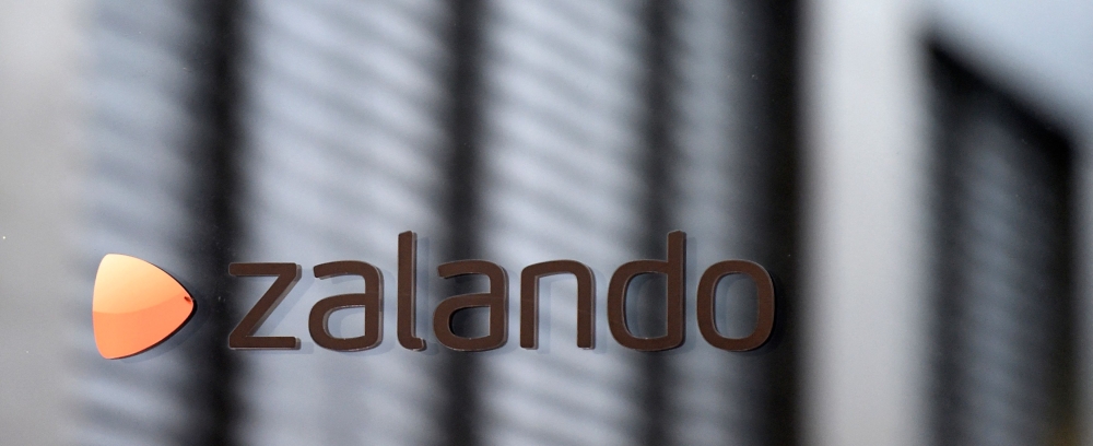 The logo of German shoes and clothing retailer Zalando is pictured at the office door in Berlin September 30, 2014. German online fashion retailer Zalando said on January 8, 2026 that it would close a distribution centre in the eastern city of Erfurt and lay off 2,700 employees to restructure its European logistics network. (Photo by Tobias Schwarz / AFP)