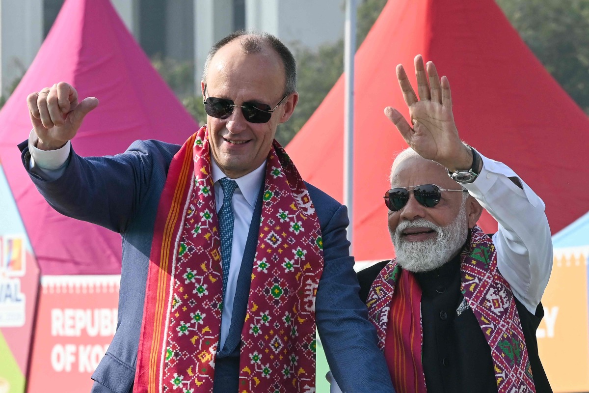 German Chancellor Friedrich Merz and Indian PM Narendra Modi wave to the crowd in Ahmedabad on January 12, 2026. (Photo by Shammi MEHRA / AFP)