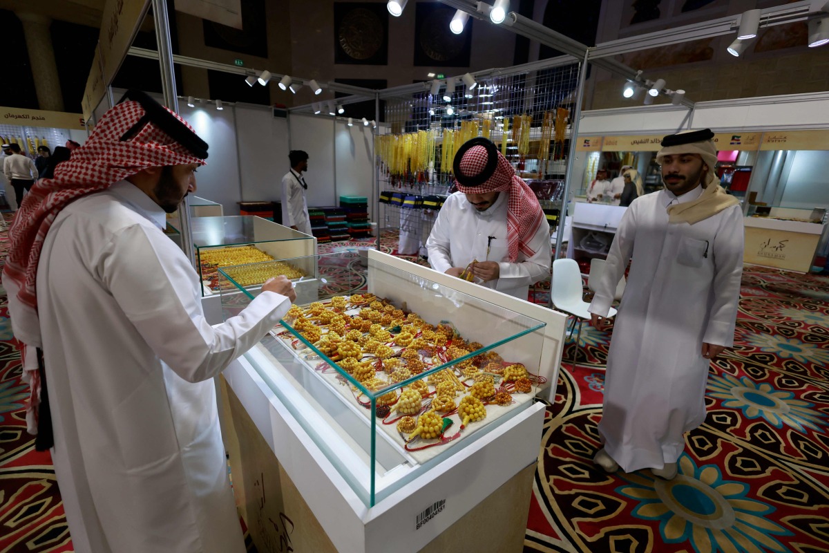 Visitors look at prayer beads at the Katara International Exhibition for Kahraman, showcasing artwork and handicrafs made with amber, at the Katara cultural village in Doha on January 13, 2026. (Photo by Karim JAAFAR)