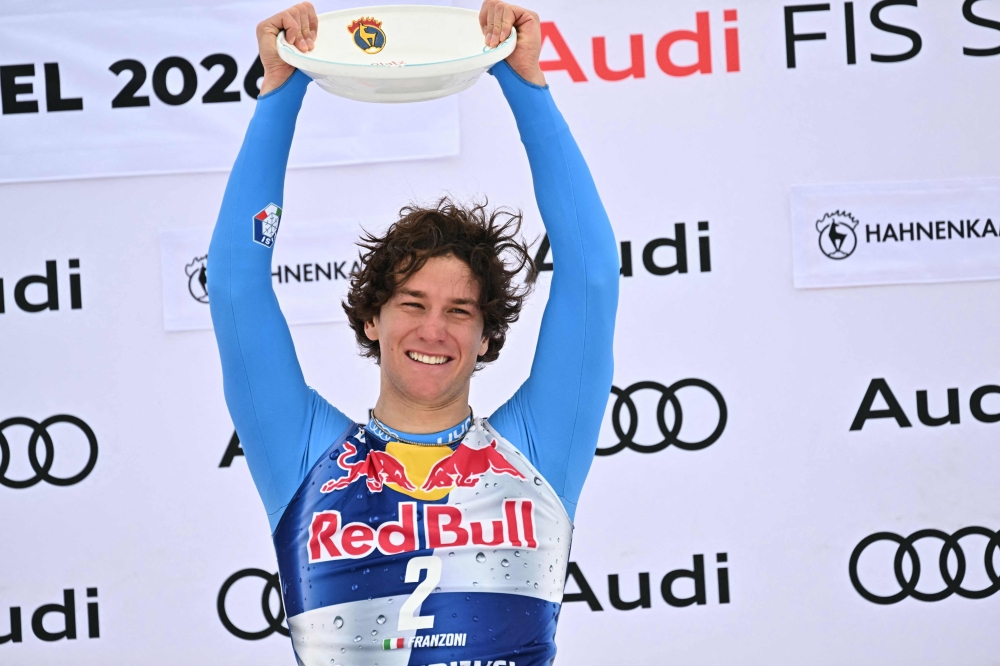 Winner Italy's Giovanni Franzoni celebrates on the podium with his trophy after the Men's Downhill event of the FIS Alpine Skiing World Cup in Kitzbuhel, Austria, on January 24, 2026. (Photo by Joe Klamar / AFP)