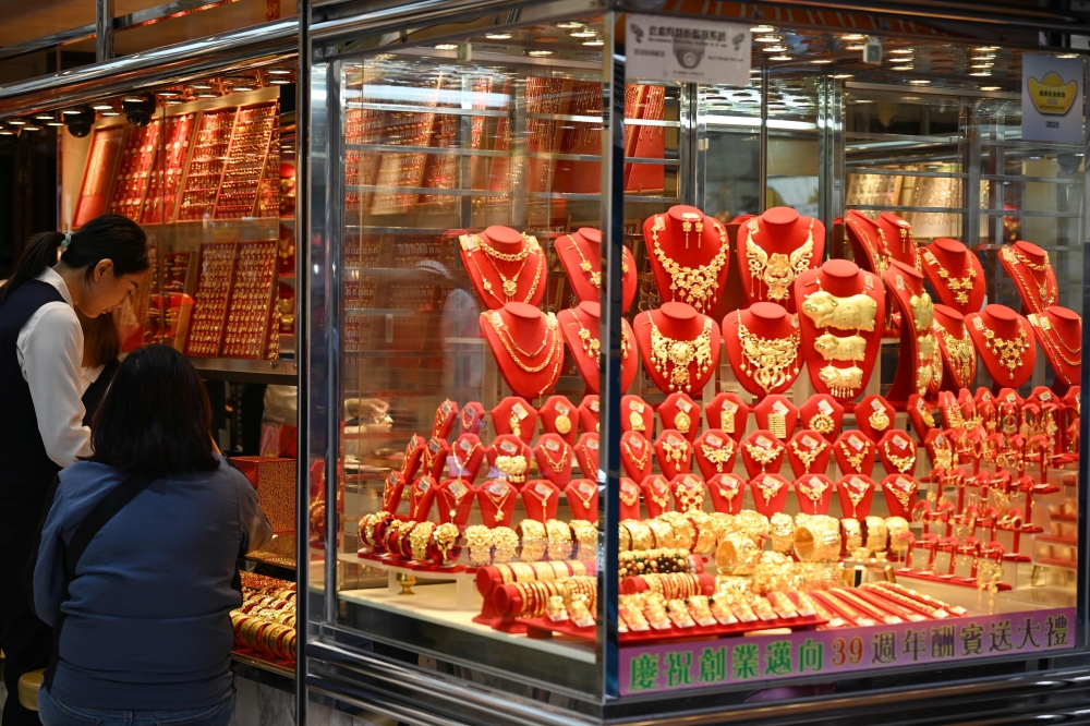 A customer (2nd L) visits a shop selling gold in Hong Kong on January 26, 2026. (Photo by Peter Parks / AFP)