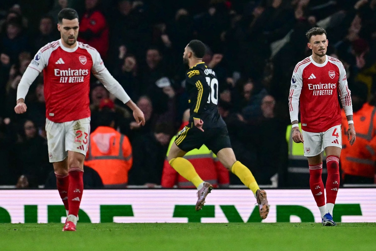 Arsenal's Spanish midfielder #23 Mikel Merino (L) and Arsenal's English defender #04 Ben White (R) react as Manchester United's Brazilian striker #10 Matheus Cunha (C) celebrates after scoring his team's third goal in the 87th minute during the English Premier League football match between Arsenal and Manchester United at the Emirates Stadium in London on January 25, 2026. (Photo by Ben STANSALL / AFP)