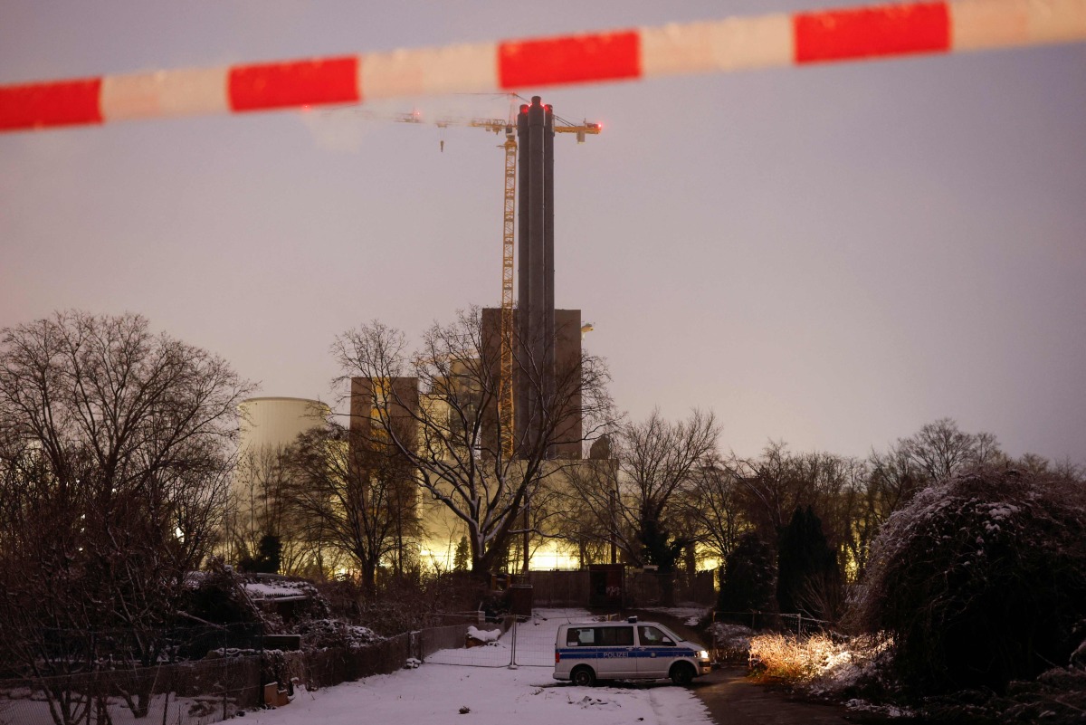 A police cordon is seen in the foreground as police and emergency personnel investigate the site of a fire of high-voltage cables on a bridge near the Lichterfelde power plant (back) on the Teltow Canal in Berlin on January 3, 2026. Photo by Odd ANDERSEN / AFP