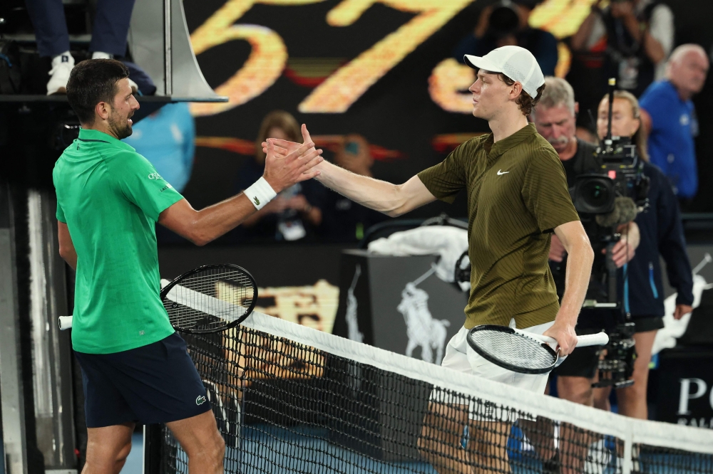 Serbia's Novak Djokovic greets Italy's Jannik Sinner after winning their men's singles semi-final match on day thirteen of the Australian Open tennis tournament in Melbourne. (Photo by DavidD Gray / AFP) 