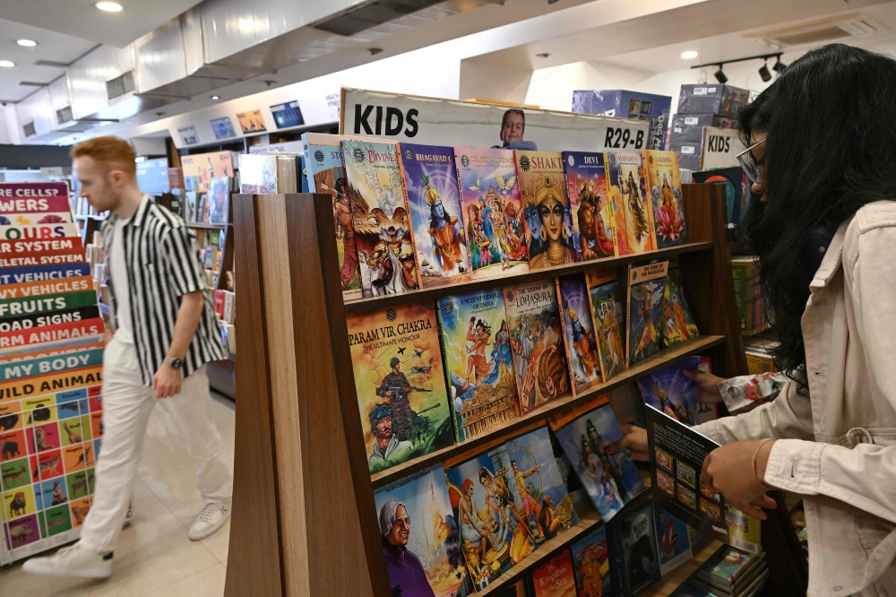 This photograph taken on January 20, 2026 shows a woman checking books by India's oldest and indigenous comic publisher Amar Chitra Katha at a store in Mumbai. (Photo by Indranil Mukherjee / AFP)