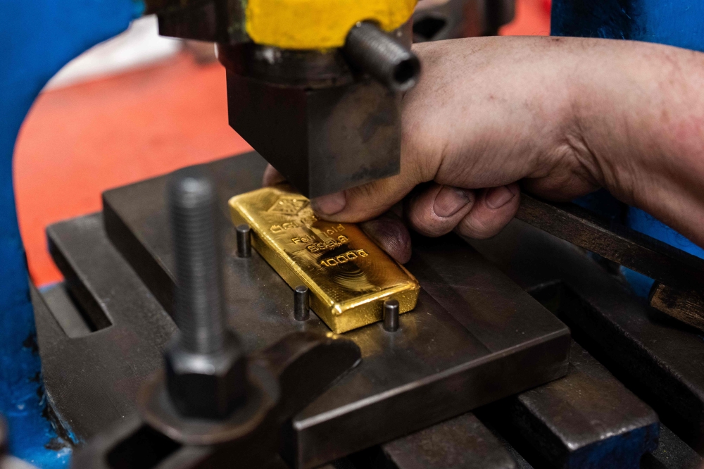 A gold bar weighing 1000 grams is minted at the Austrian Gold and Silver Refinery (Oegussa) in Vienna, Austria, on February 3, 2026. (Photo by Georg Hochmuth / APA / AFP) 