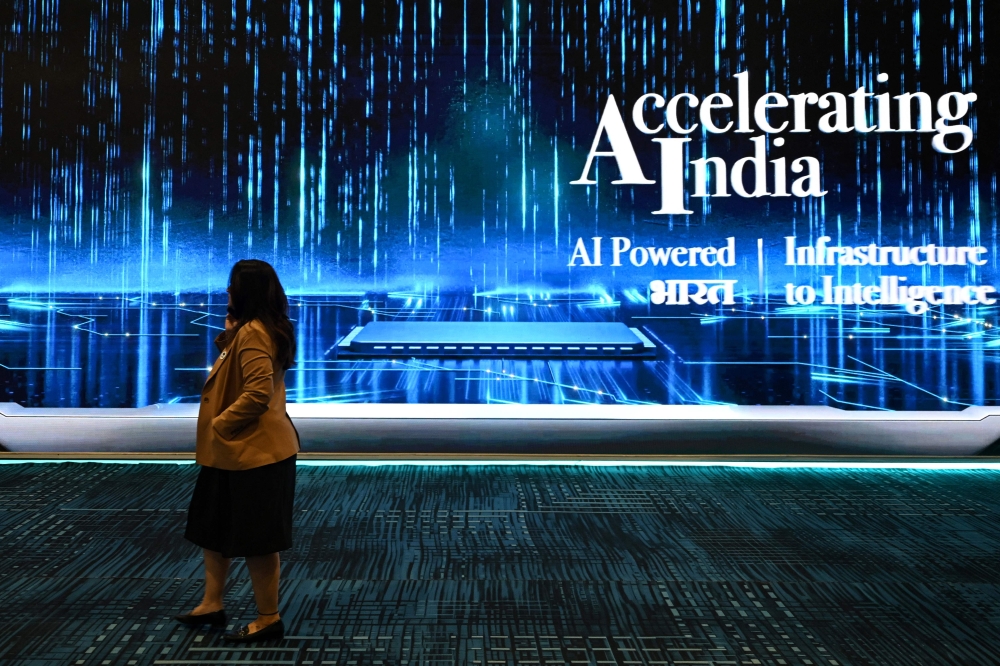 A visitor walks past a display at the AI Impact Summit in New Delhi on February 17, 2026. (Photo by Arun Sankar / AFP)