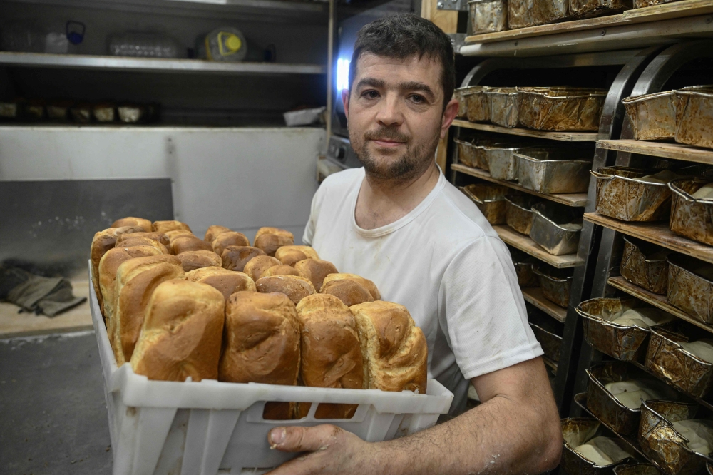 French volunteer baker Loic Nervi holds a basket of freshly baked bread in his mobile bakery in Borodyanka, Kyiv region on February 19, 2026. (Photo by Genya Savilov / AFP)