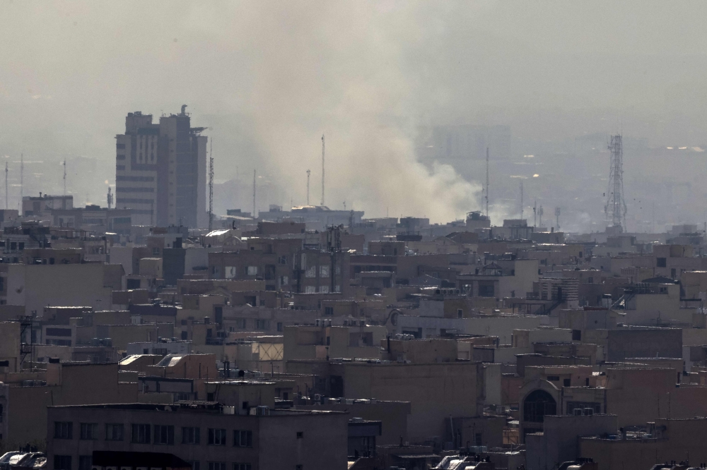 A plume of smoke rises following a reported explosion in Tehran on February 28, 2026. Two loud blasts were heard in Tehran on February 28 morning (Photo by Atta Kenare / AFP)