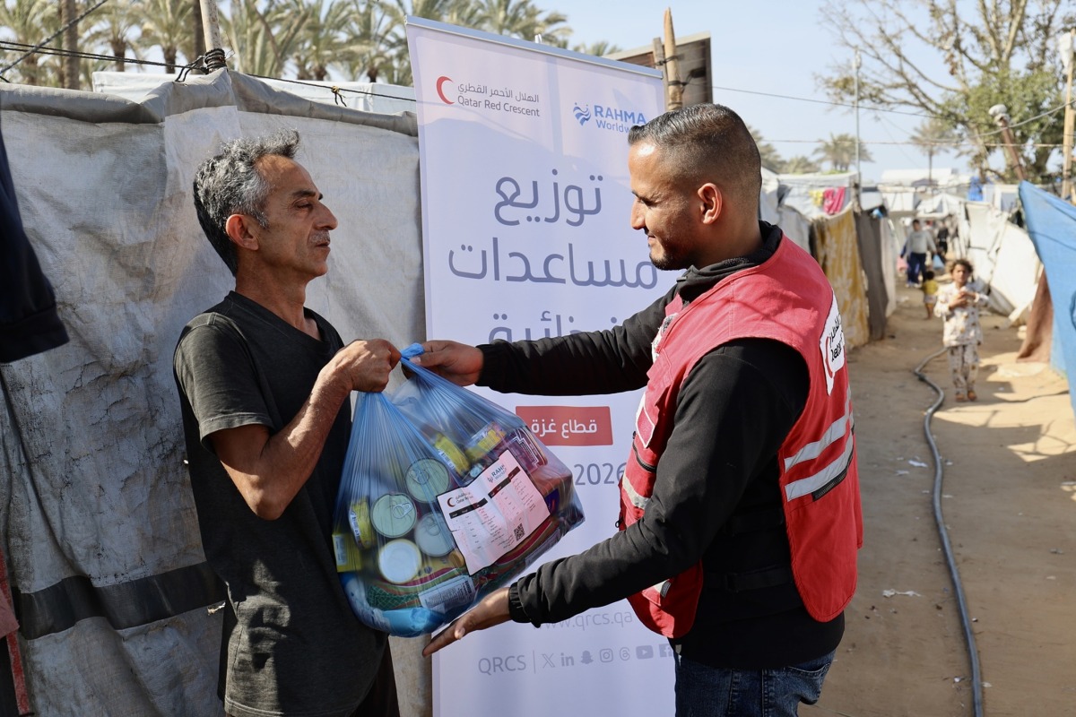 A QRCS representative hands over food aid to displaced people in Gaza. 