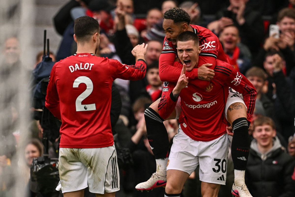 Manchester United's Slovenian striker #30 Benjamin Sesko (R) celebrates with Manchester United's Brazilian striker #10 Matheus Cunha (top R) and teammates after scoring his team's third goal during the English Premier League football match between Manchester United and Aston Villa at Old Trafford in Manchester, north west England, on March 15, 2026. (Photo by Oli SCARFF / AFP)
