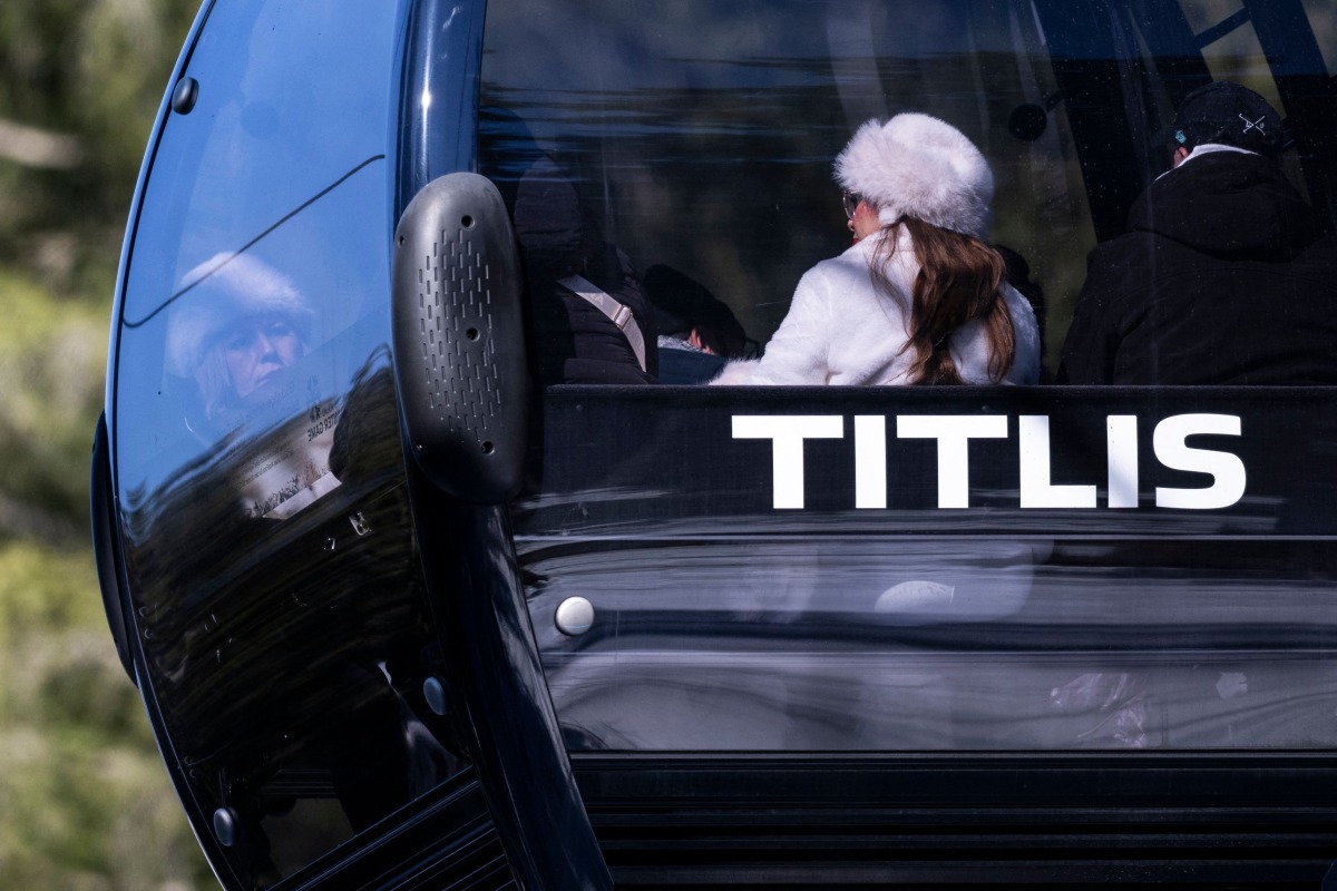 Tourists sit in a gondola cabin going down at the Titlis-Engelberg ski area in Engelberg, central Switzerland, on March 18, 2026, after a gondola cabin detached from its cable and crashed. (Photo by Ennio LEANZA / AFP)