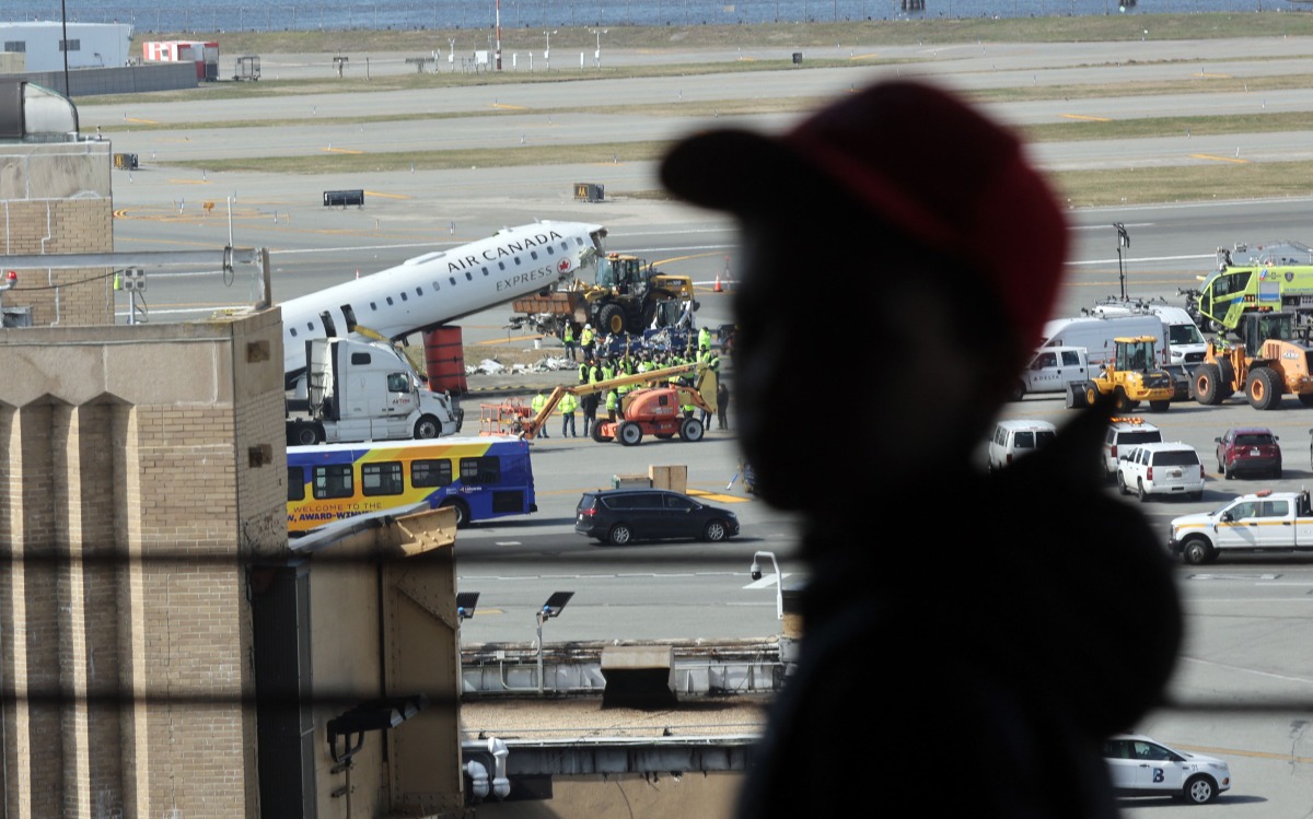 A child looks out at an Air Canada Express plane that collided Sunday night with a fire truck on the tarmac at LaGuardia Airport on March 25, 2026 in New York City. Photo by SPENCER PLATT / GETTY IMAGES NORTH AMERICA / Getty Images via AFP