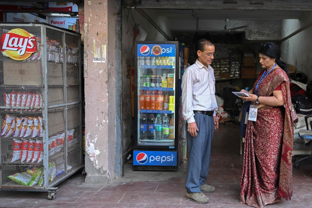 Sukhwinder Kaur (R), a census enumerator and a school teacher, collects details of housing and amenities during a door-to-door survey in the first phase of the census at a residential area in New Delhi on April 20, 2026. (Photo by Arun Sankar / AFP)