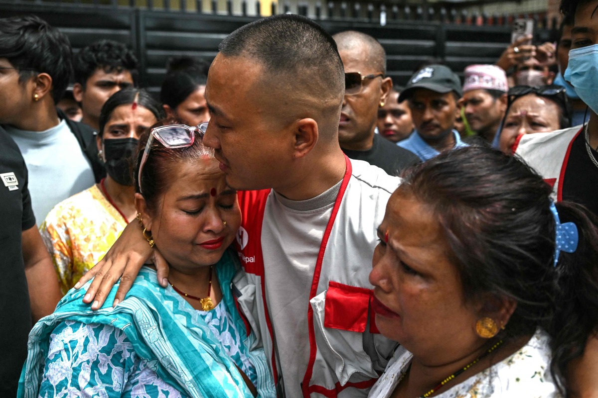 Sudan Gurung (C), a key figure among the Gen Z protesters, meets with family members of a victim, who died during anti-corruption clashes with security personnel, outside the Tribhuvan University Teaching Hospital in Kathmandu on September 13, 2025. Photo by Arun SANKAR / AFP