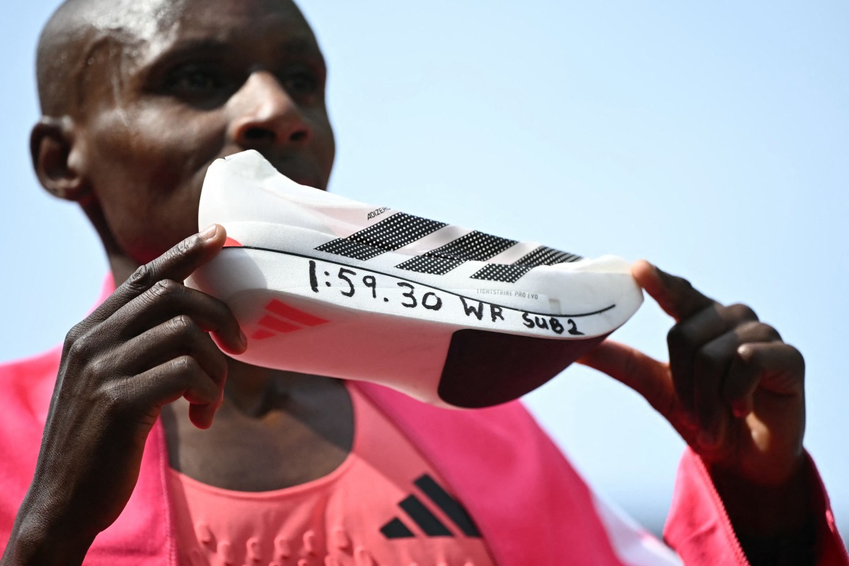 Kenya's Sabastian Sawe poses with his new world record time written on his running shoe at the finish of the 2026 London Marathon in central London on April 26, 2026. (Photo by JUSTIN TALLIS / AFP) / “Restricted to editorial use - sponsorship of content subject to LMEL agreement”.