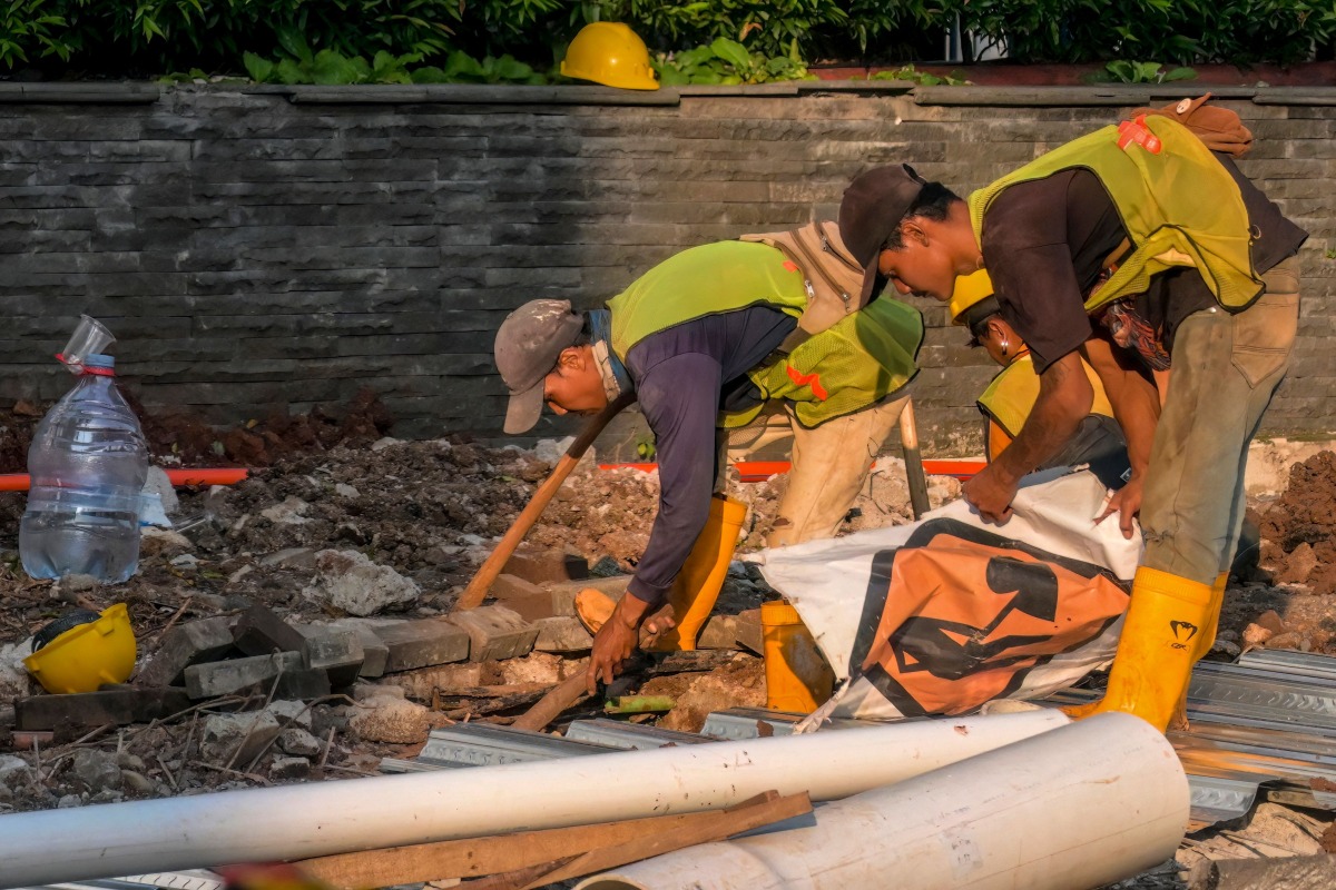 A road construction crew works at dusk in Jakarta on May 6, 2026. (Photo by BAY ISMOYO / AFP)