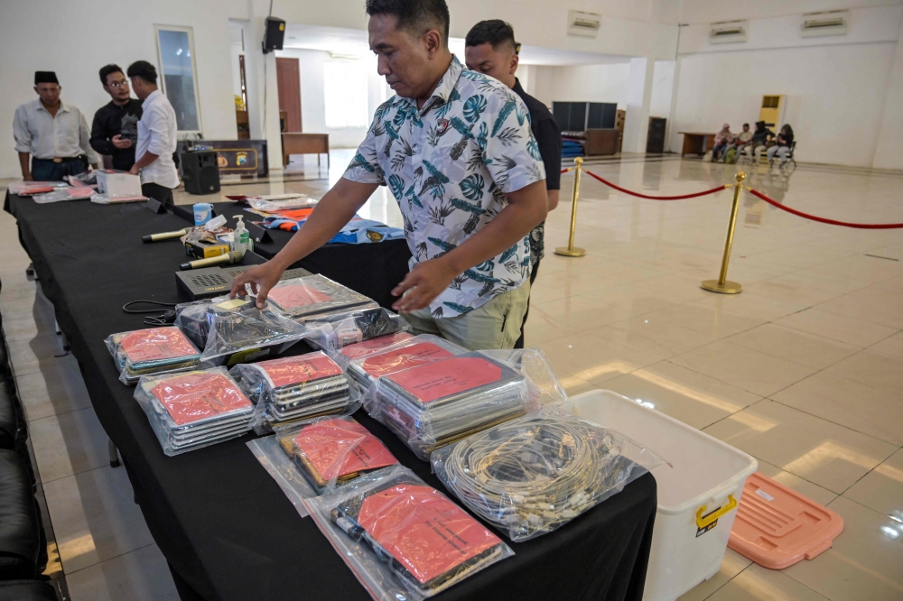 Indonesian police display evidence before authorities held a press conference following the arrest of dozens of suspects in an online fraud case in Surabaya (Photo by Juni Kriswanto / AFP)