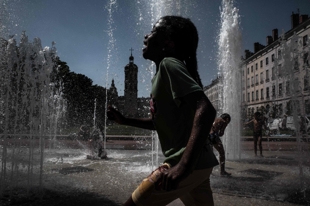 Children cool off in a fountain in Lyon on May 27, 2026 as a heatwave hits France. (Photo by Jeff Pachoud/ AFP)