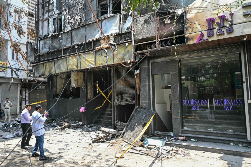 Forensics team members take photographs of the site following a fire that broke out at a hotel in New Delhi (Photo by Arun Sankar / AFP)