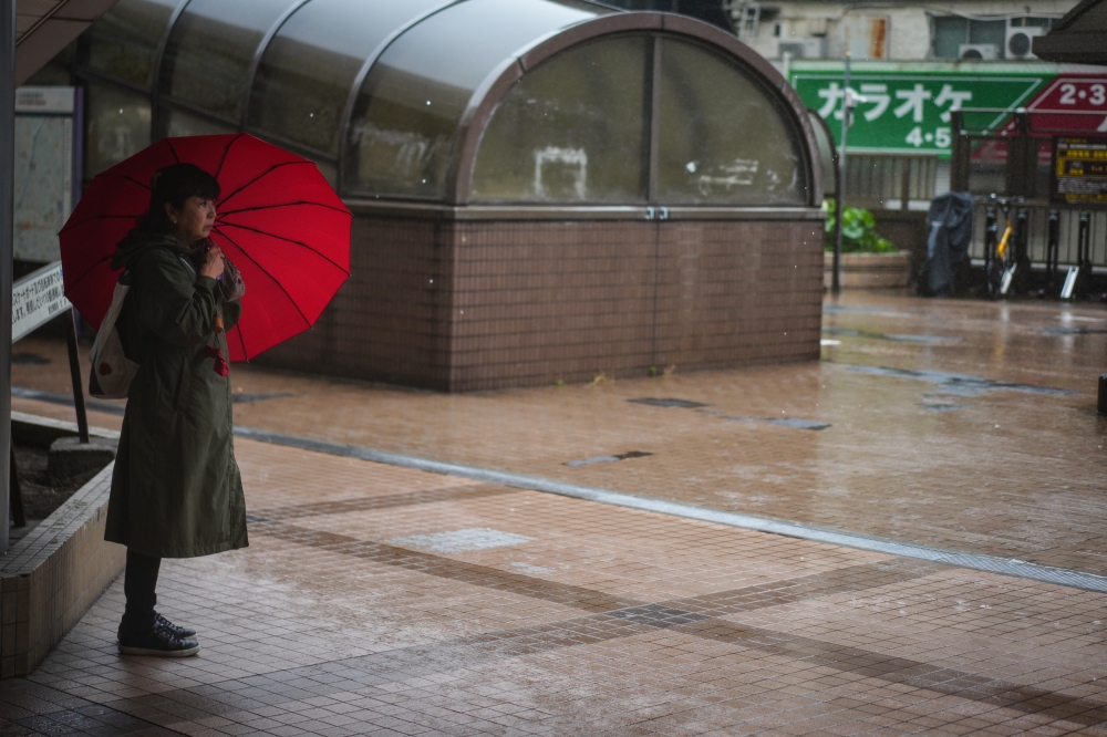 (FILE PHOTO) A woman holding an umbrella stands on a street in rain brought by Typhoon Jangmi in Tokyo, Japan, June 3, 2026. (Xinhua/Jia Haocheng)
