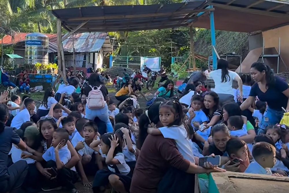 This frame grab made from UGC video footage courtesy of Deped Mahayahay Elementary School shows huddled schoolchildren in a field reacting during an 7.8 magnitude earthquake in Malita town, Davao del Sur province on June 8, 2026. (Photo by Courtesy of Deped Mahayahay Elementary School / AFP) 