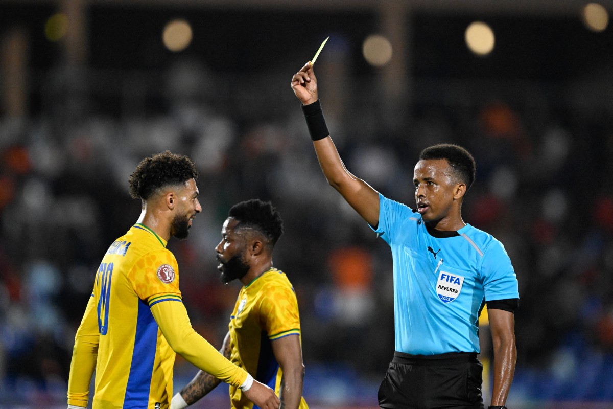 Gabon's forward #20 Denis Bouanga is shown the yellow card by Somali referee Omar Abdulkadir Artan during the Africa Cup of Nations (CAN) Group F football match between Gabon and Ivory Coast at the Grand Stadium in Marrakech on December 31, 2025. Photo by Khaled Desouki / AFP