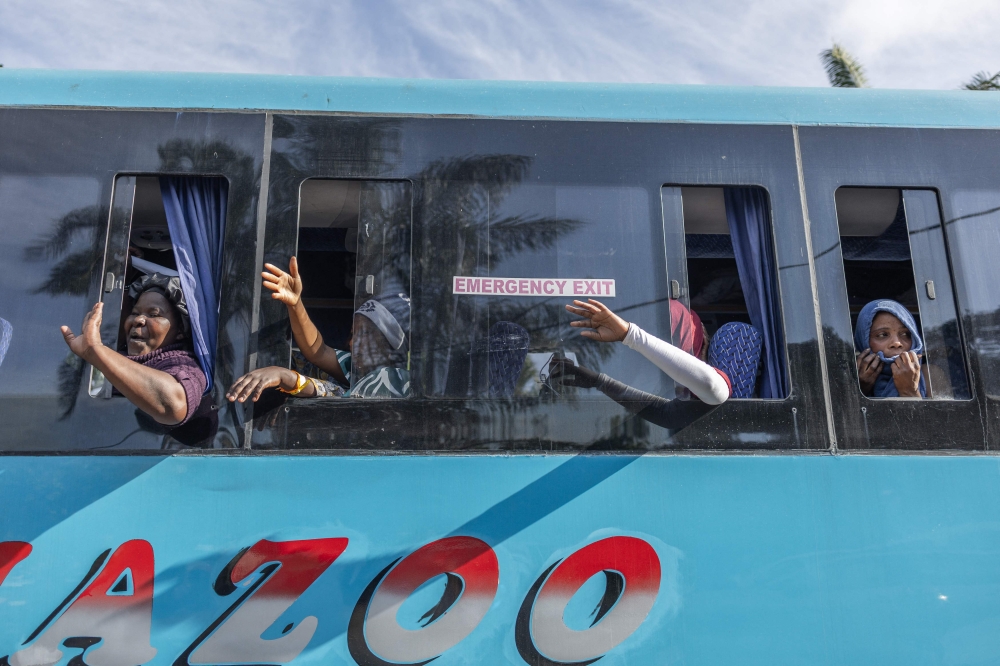Migrants wave to people their goodbyes as the first of seven buses leave the Sherwood Park in Durban on June 14, 2026. (Photo by RAJESH JANTILAL / AFP)
 