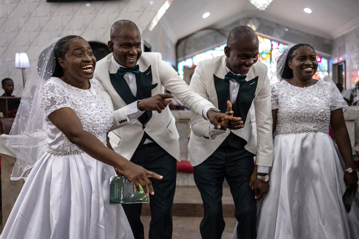 Grooms and brides dance during their wedding ceremony at the Bishop Akinyele Memorial Anglican Church in Ibadan, on June 20, 2026. (Photo by OLYMPIA DE MAISMONT / AFP)