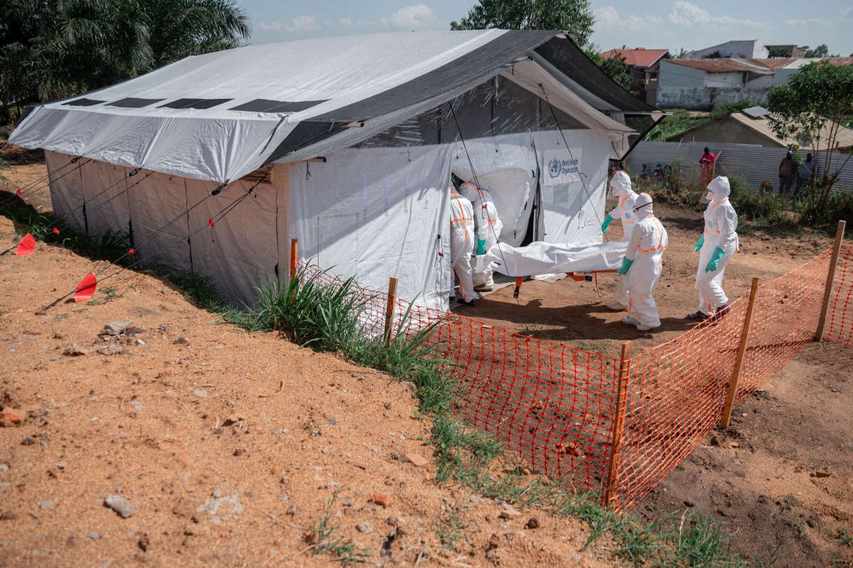 Members of specialized response teams enter the morgue of the Evangelical Medical Center of Nyankunde (CME) with the body of a person who died from Ebola virus disease to allow relatives to pay their last respects after washing, disinfection and safe body-wrapping procedures in Bunia, Ituri Province, Democratic Republic of Congo, on June 13, 2026. (Photo by Jospin Mwisha / AFP)