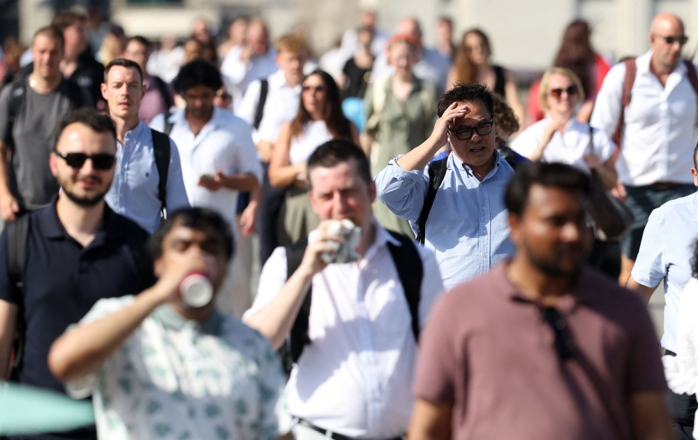 Commuters walk in the sun as they cross London Bridge, during a heatwave, in central London on June 24, 2026. (Photo by Toby Shepheard / AFP)