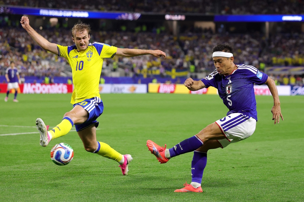 Yuto Nagatomo #5 of Japan crosses the ball while Benjamin Nygren #10 of Sweden attempts to block. Alex Slitz/Getty Images/AFP