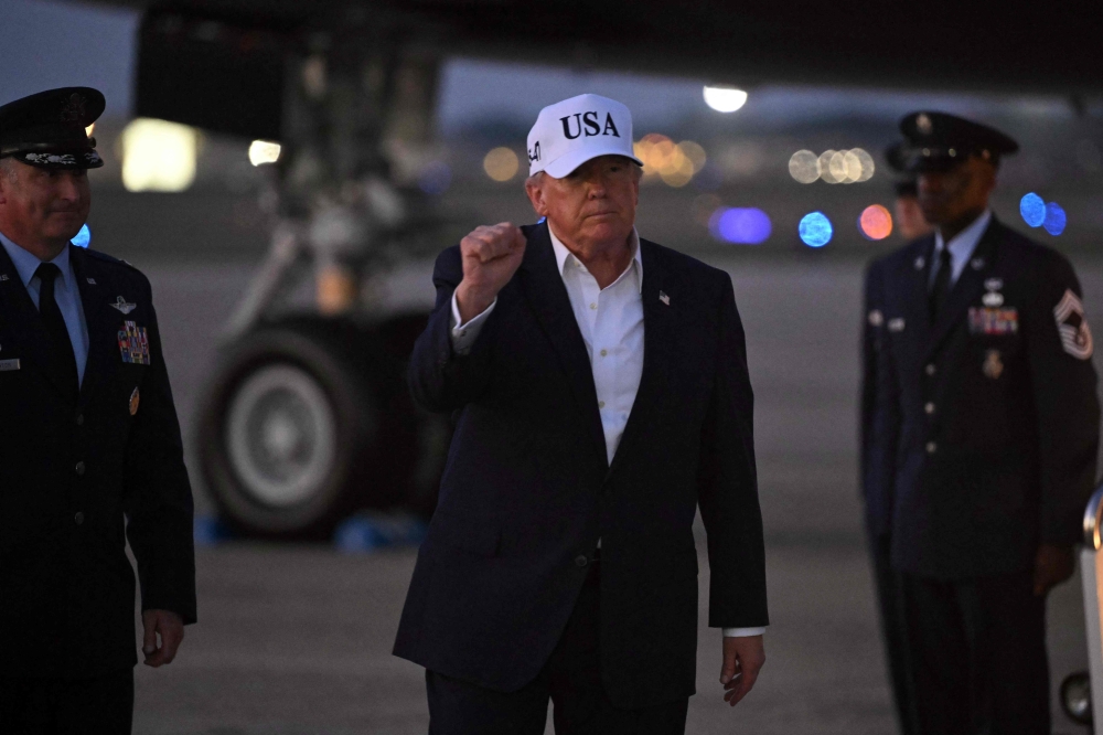 US President Donald Trump gestures toward reporters after disembarking from Air Force One at Joint Base Andrews, Maryland on July 1, 2026. (Photo by Saul Loeb / AFP)