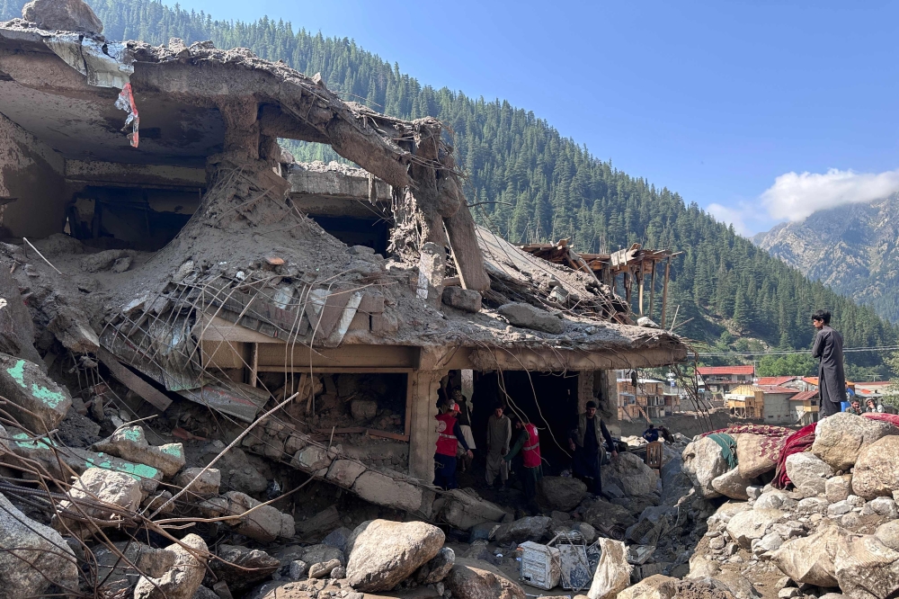 Afghan men search the debris of destroyed shops after flash floods hit Parun town in Afghanistan's Nuristan province, on July 21, 2026. (Photo by AFP)