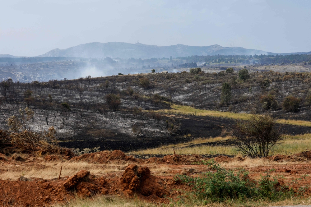 Smoke from a wildfire is seen near the town of Albendiego, in the Guadalajara province north of Madrid, on July 22, 2026. A wildfire that broke out on July 16 in La Mierla area, near Guadalajar has devastated 32,000 hectares and caused the evacuation of several hundred people. (Photo by Pierre-Philippe MARCOU / AFP)