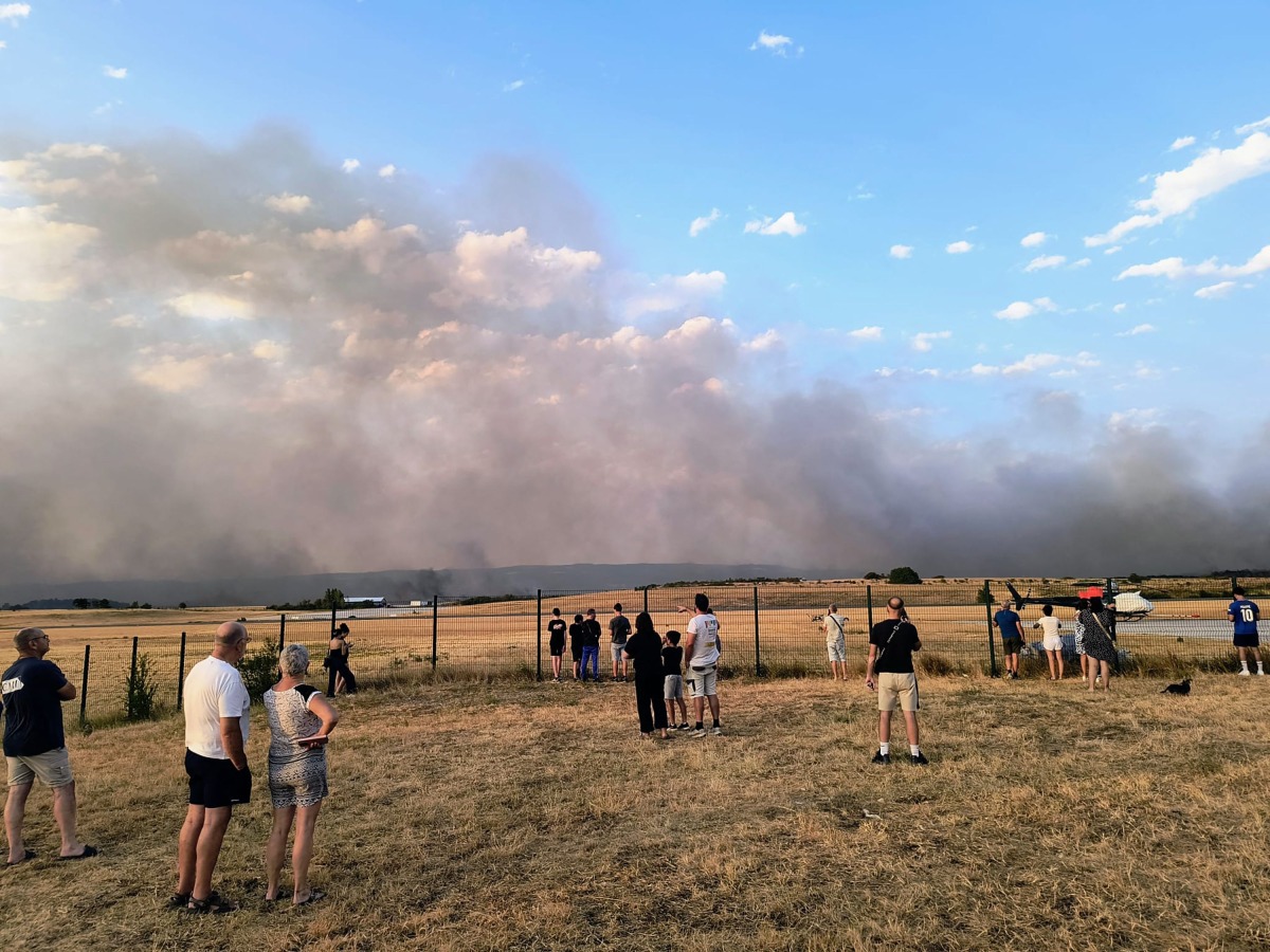 Bystanders look on as fire and smoke billow across Castres-Mazamet aerodrome, near Labruguiere in south-western France on July 24, 2026. (Photo by Daniel ABELOUS / AFP)

