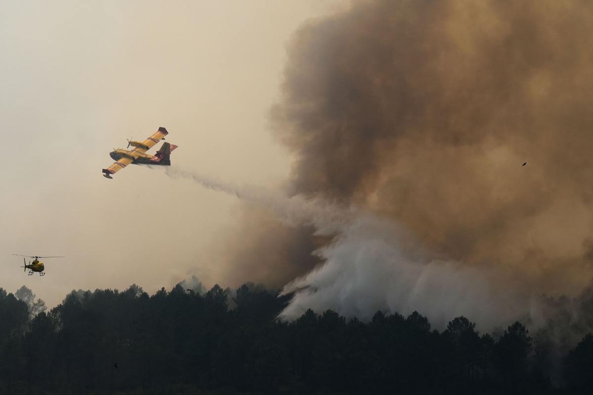 This aerial view taken from a Civil Security helicopter shows an aircraft dropping a load of water over a wildfire near Saint-Jean-d'Illac, southwestern France, on July 28, 2026. (Photo by Baz Ratner / POOL / AFP)