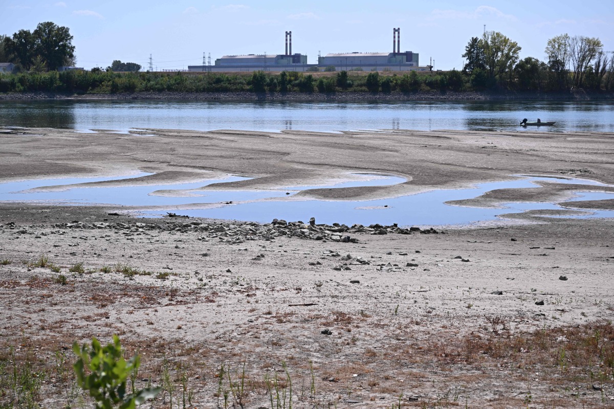 :The dried-up Danube riverbed is pictured with the Paks power plant at the background, near Dunaszentbenedek, close to Paks town on July 31, 2026. (Photo by Attila KISBENEDEK / AFP)
