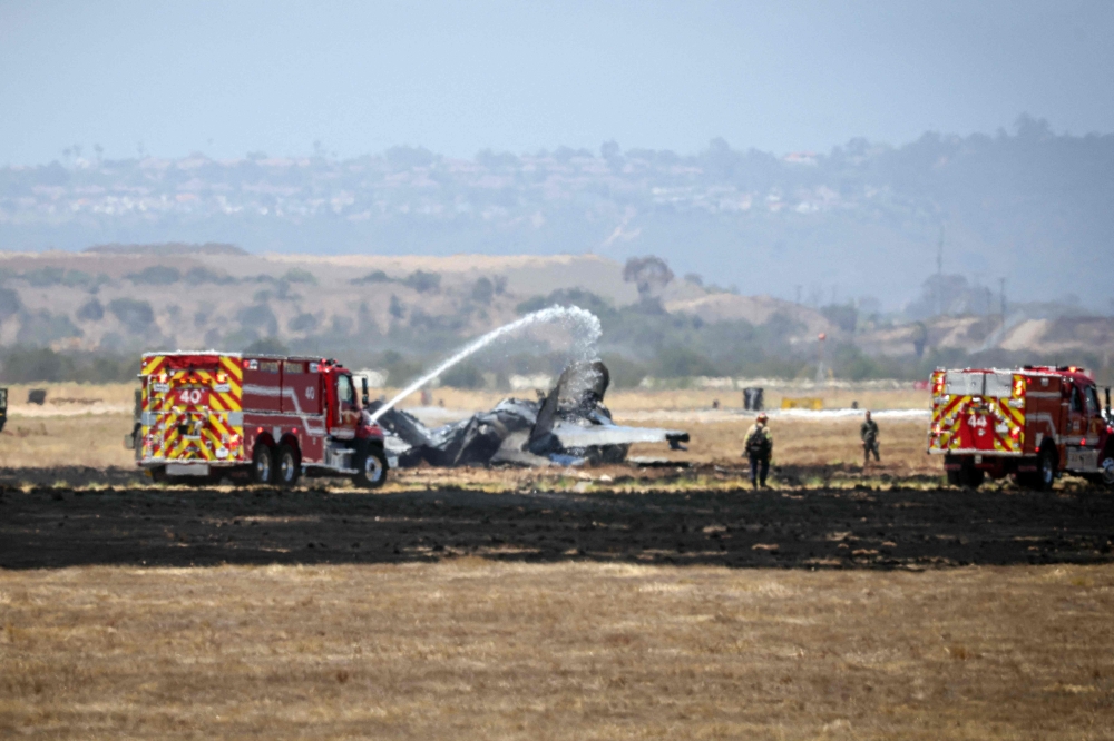 Fire crews spray down the wreckage of a US Marines’ F-35B fighter jet after it crashed into a field near Miramar Air Base in San Diego, California, on July 31, 2026.(Photo by SANDY HUFFAKER / AFP)