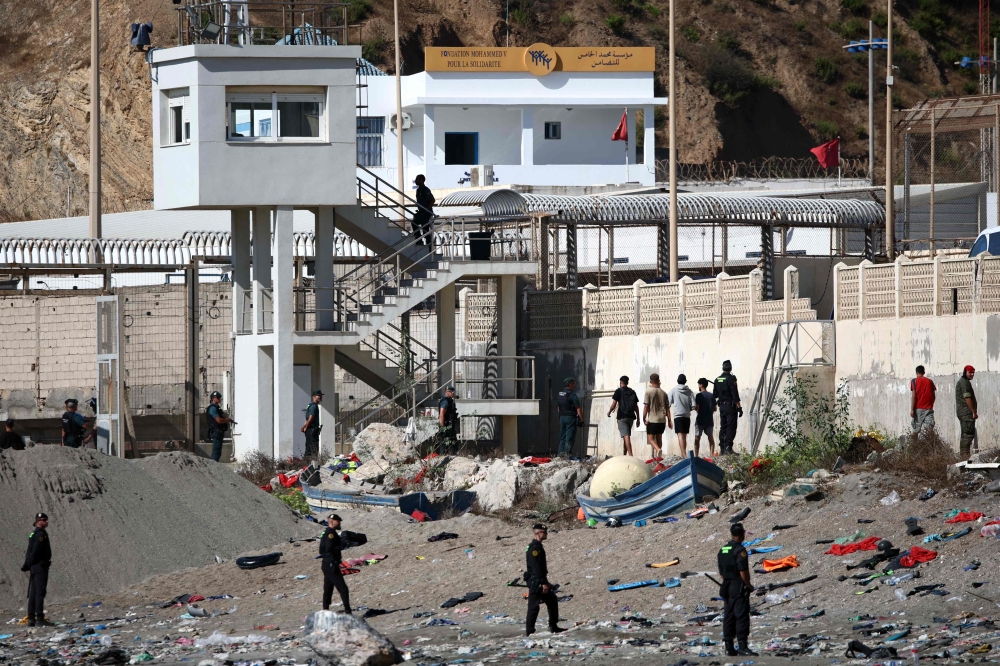 Some migrants arrive at the border post with the intention of crossing back into Morocco as members of the Spanish armed forces keep watch over the area in the Spanish enclave of Ceuta on August 2, 2026. (Photo by Henry Nicholls / AFP)
 