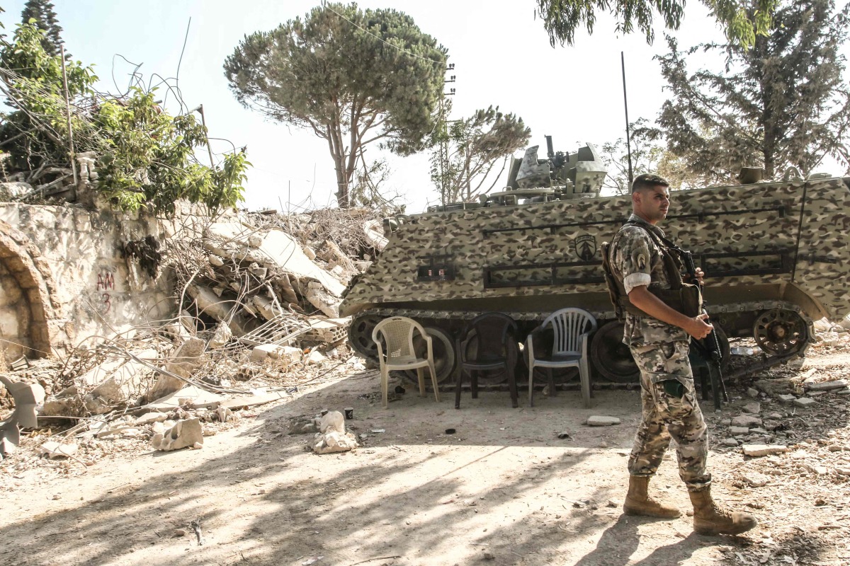 A Lebanese army soldier stands on guard by his armoured vehicle in the southern Lebanese village of Zawtar al-Gharbiyah which was previously badly damaged by the Israeli military on August 8, 2026. (Photo by Mahmoud ZAYYAT / AFP) /