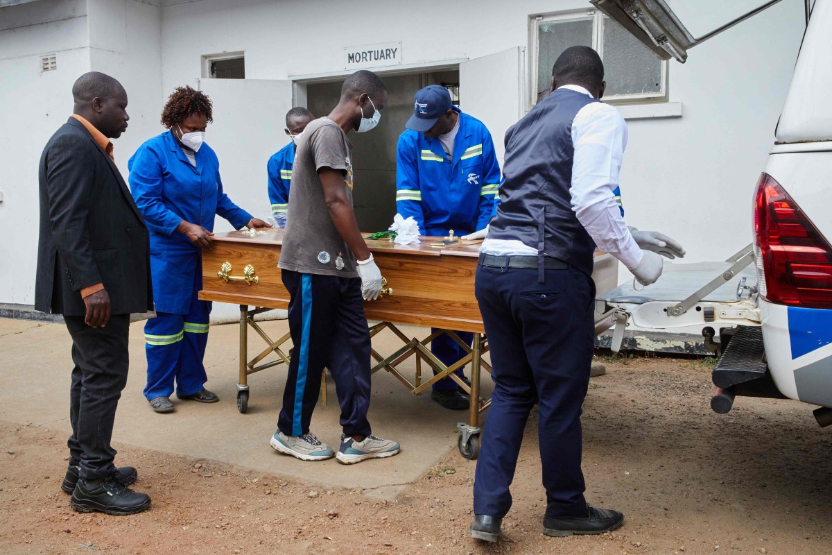 Takemore Malunga (L) watches as pallbearers carry the coffin of his maternal uncle, a victim of the capsized passenger ferry, at the Kariba Hospital mortuary in Kariba, on August 14, 2026. (Photo by Jekesai NJIKIZANA / AFP)