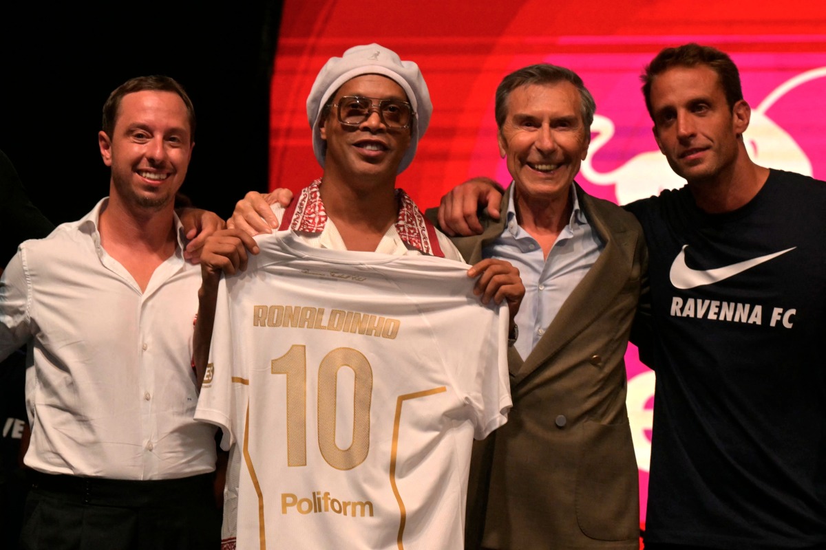 Newly recruited Brazilian football player Ronaldinho poses on stage with the jersey of Ravenna FC next to the president of the club, Ignazio Cipriani (R) during the team presentation in Marina di Ravenna on August 20, 2026. (Photo by Stefano RELLANDINI / AFP)
