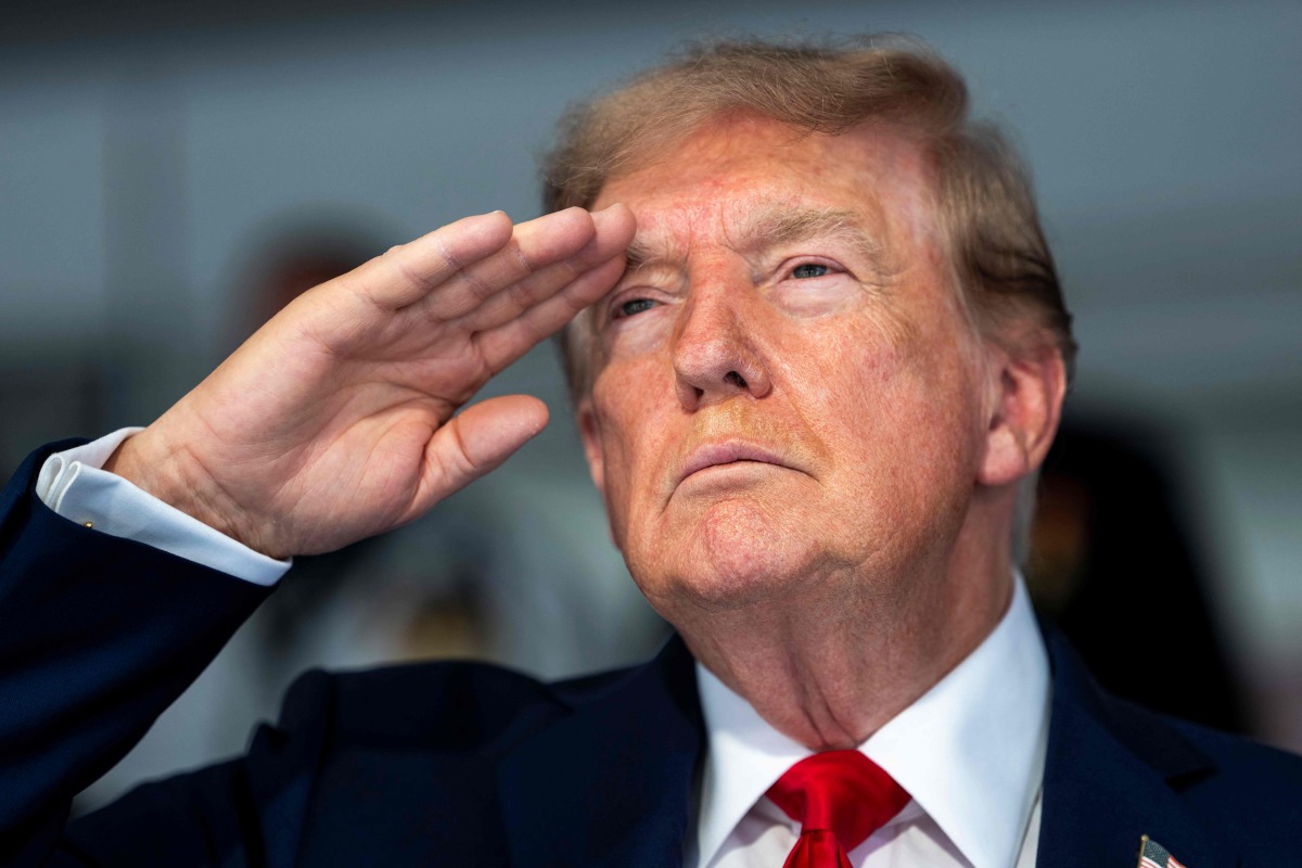 US President Donald Trump salutes during the national anthem at the start of the race, during the Freedom 250 Grand Prix Race on the streets of Washington, DC, on August 23, 2026.(Photo by Doug MILLS / AFP)