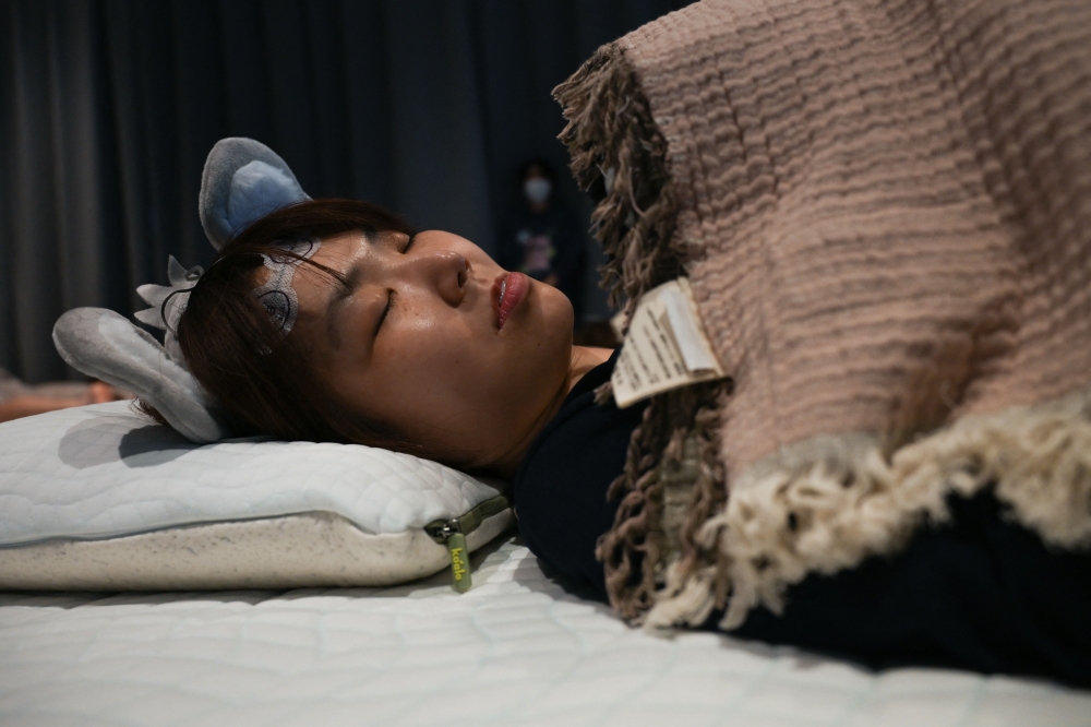 An attendee takes part in a sleep competition organized by a mattress brand in Tokyo on October 5, 2026. (Photo by Selim Chtayti / AFP)