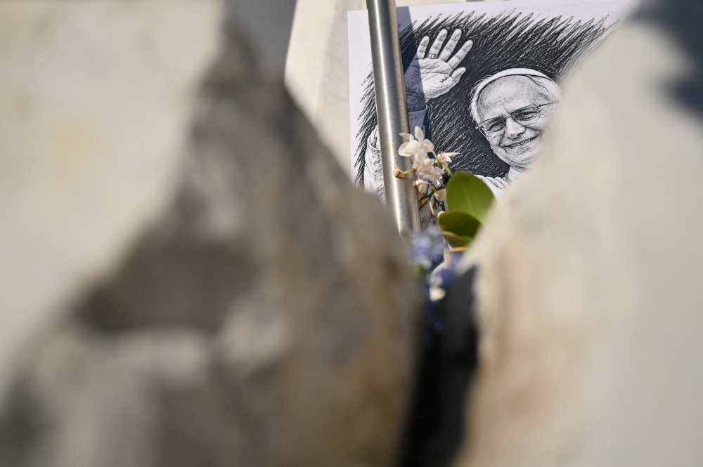 A drawing of Pope Leo XIV is laid at the statue of John Paul II outside the Gemelli University Hospital in Rome on October 16, 2026 (Photo by Alberto Pizzoli / AFP)